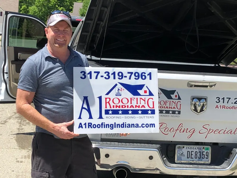 James Moore, owner, holding an A1 Roofing Indiana sign
